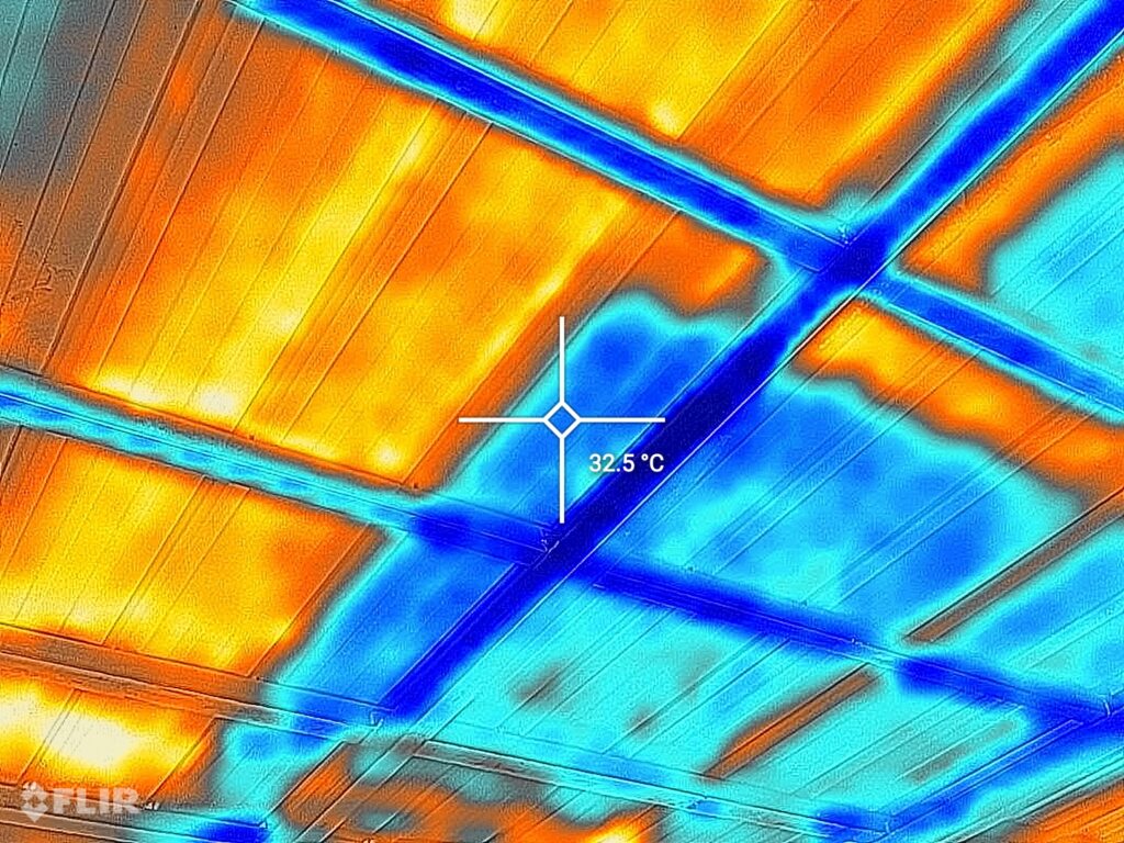 Aufnahme mit einer Wärmebildkamera eines Blechdachs. Klar sind die Solarpannele zu erkennen. Das Blech unter den Solarpannels ist mit 32,5 Grad viel kühler als die Dachfläche ohne Solarpannels mit über 48°